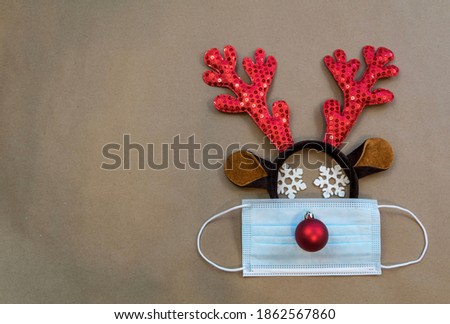Festive reindeer antlers with face mask and ornaments for winter, Christmas, New Year's, December, brown paper background flat lay 