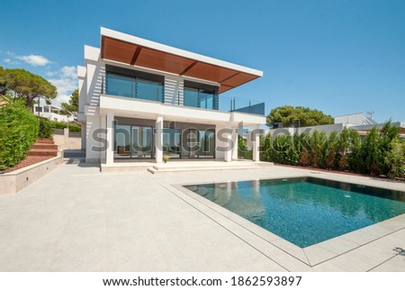 The modern facade of a luxury villa with a large swimming pool. Luxury MODERN property. Royalty-Free Stock Photo #1862593897