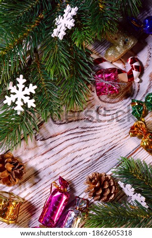 Christmas background. Artificial spruce branches with cones and New Year's toys on a wooden surface. Vertical, free space in the center, top view.