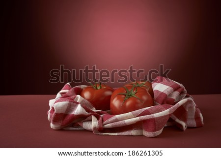 fresh red tomatoes on checkered tablecloth, with red background