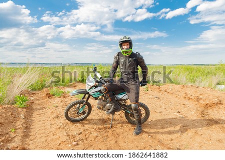 A man in motorcycle equipment sits on an enduro motorcycle. Motocross sport. Extreme off-road race.