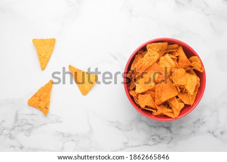 A flatlay picture of nachos in a bowl on marble table. Nachos are a Mexican regional dish from northern Mexican often served as a snack or appetizer. 