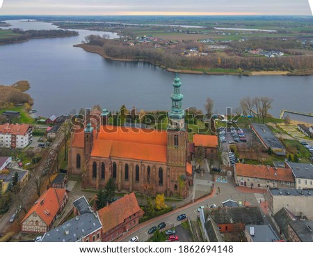 Aerial view of the historic cathedral in Chełmza (Pomerania, Poland), gothic brick church with  red roof and high tower as main focus, city and lake in the background, cloudy day in November