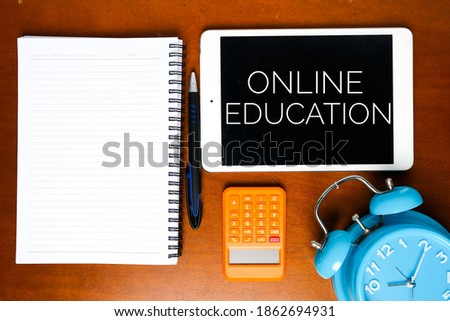 A picture of online education on tablet with notebook pen, calculator and alarm clock. Online education is the best method for schooling during covid-19 outbreak.
