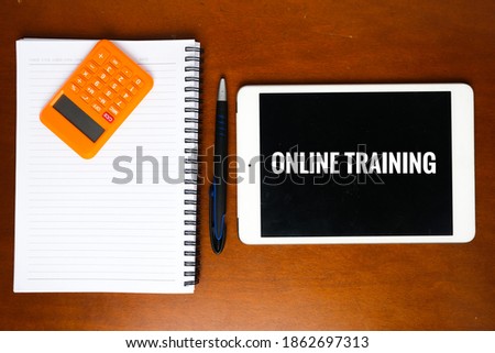 A picture of tablet with online training word, pen, calculator and notebook.