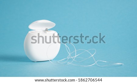 Container with dental floss. Floss on blue background. White dental floss case isolated. Open dental floss container Royalty-Free Stock Photo #1862706544