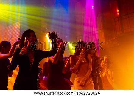 Silhouette image of people dance in disco night club to music from DJ on stage . New year night party and nightlife concept .