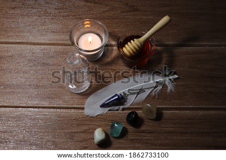 Honey Spell consists of an empty glass jar, a lucky stone, a feather and a white candle. This picture is used to write about magic.