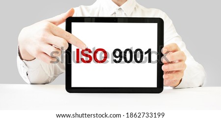Text ISO 9001 on tablet display in businessman hands on the white bakcground. Business concept