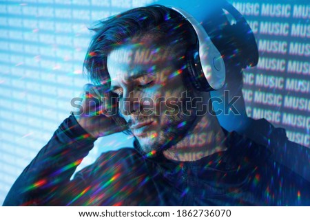 Portrait of man in headphones listening music. Blue neon light background.