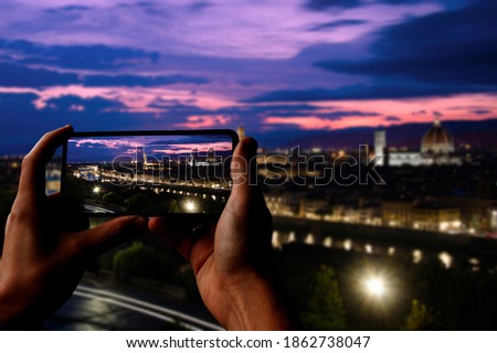 Tourist taking photo of Florence after sunset from Michelangelo square, Florence, Italy. Beautiful panoramic view of Duomo Santa Maria Del Fiore and tower of Palazzo Vecchio during evening.