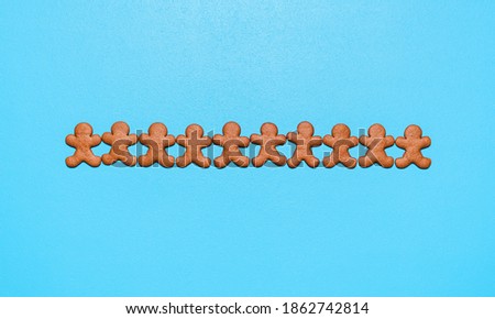 Above view with homemade gingerbread cookies on a blue background. Flat lay with gingerbread man cookies aligned in a row on the table