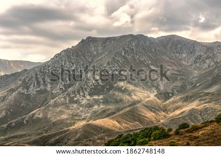 The first rays of the autumn sun in the Syunik mountains on the way to the city of Meghri through dark rain clouds
