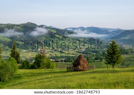 Morning Landscape in Bucovina, Romania. Foggy hills mountains and haystack