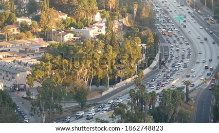 Busy rush hour intercity highway in metropolis, Los Angeles, California USA. Urban traffic jam on road in sunlight. Aerial view of cars on multiple lane driveway. Freeway with automobiles in LA city. Royalty-Free Stock Photo #1862748823