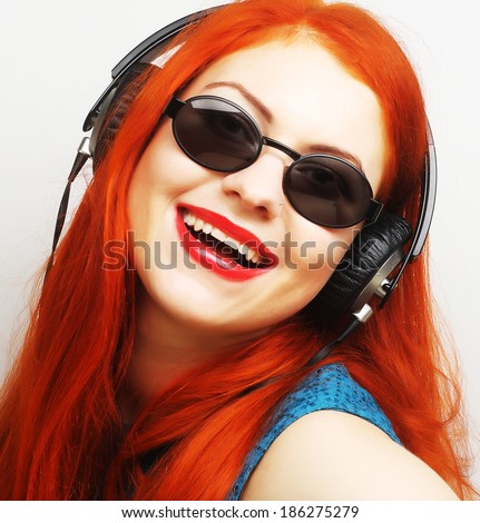 Young bright redhair woman with headphones listening music 