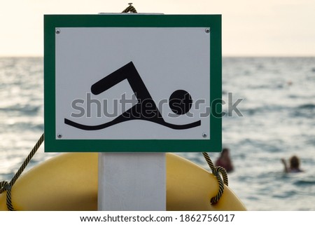 Beach sign in a green frame with the image of a floating person on the background of the sea. Selective focus.