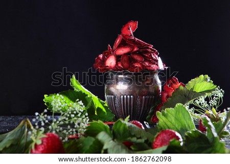 Dried strawberry fruit in an old metal vase. Natural product. For vegetarians. Photo on a black background. Copy space.