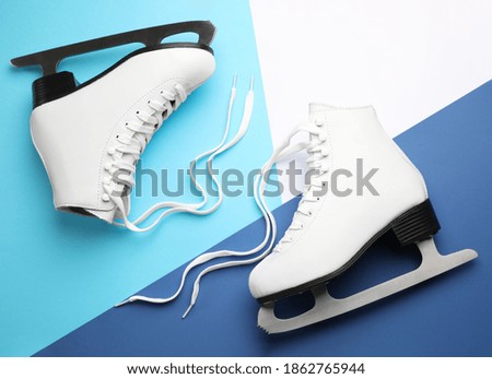Pair of white ice skates on color background, flat lay