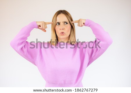 Picture of young woman make crazy gesture and dressed in casual pink sweater. Over white background