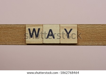 text the word way from gray wooden small letters with black font on an pink table