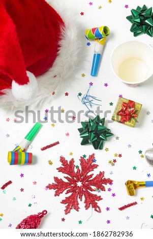 Christmas and New Year decorations with confetti, gift boxes, Santa Claus hat and party blowouts. Colorful party flat lay.