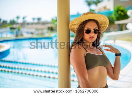Cheerful plus size teenage girl wearing hat and sunglasses enjoying near the pool. smiling, happy, positive emotion, summer style.