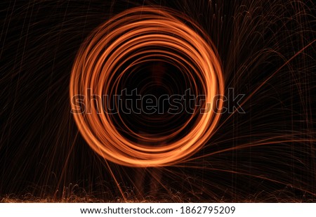 Burning Steel Wool spinning. Showers of glowing sparks from spinning steel wool. Visible noise due to low light condition.  Royalty-Free Stock Photo #1862795209