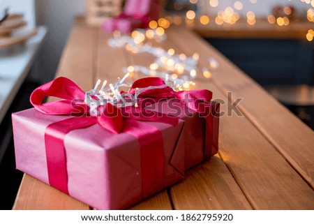 Gifts in red. Boxes with gifts on the table. Lights and bokeh in the background. Christmas card.