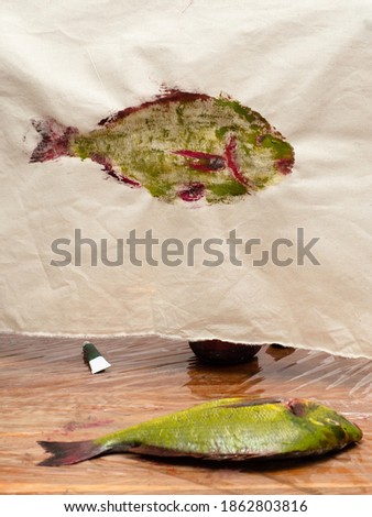 masterclass for Fish Drawing in Technique Monotype - yellow and green colored Orata fish on wooden table and its print on calico fabric