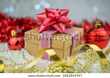 surprise gift with a red bow on the snow on a bokeh background for the new year winter holiday and valentine's day with a golden serpentine