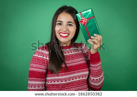 Young beautiful girl holding gift over isolated white background smiling very happy