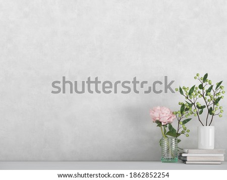 Modern room decoration. flower,  plant and books on white shelf, table against white colored wall. 