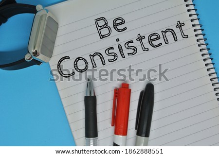 BE CONSISTENT - handwriting on a notebook with pen and smart watch. Selective focus.