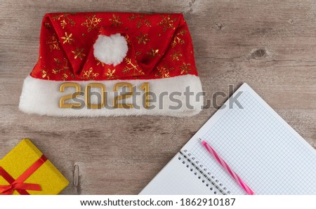 Santa Claus hat with numbers 2021 and daily planner. the concept of making wishes at Christmas. wishlist on a wooden background