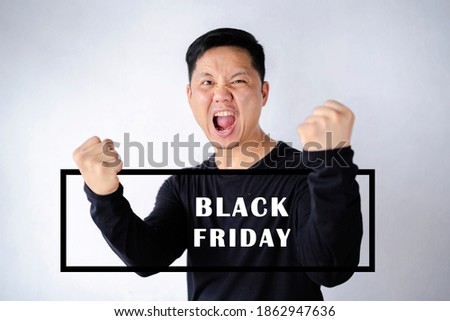 Black Friday, Happy winner. Happy young handsome man gesturing and keeping mouth open while standing against gray backgroun. 