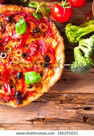 Delicious italian pizza on wooden table with fresh vegetable.