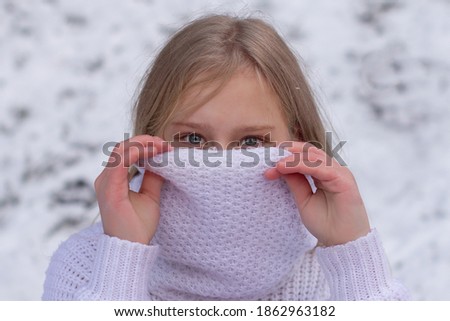 close up face of a beautiful cute teenage girl blonde white knitted scarf cover your mouth can see beautiful gray eyes winter
soft focus