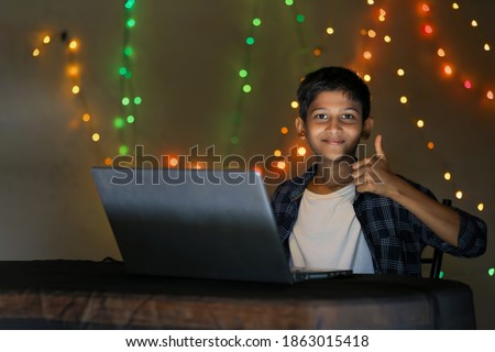 Cute indian little child using laptop and showing thumps up