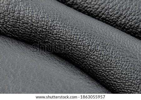 A macro shot of black leather with blue stitching on the sides.