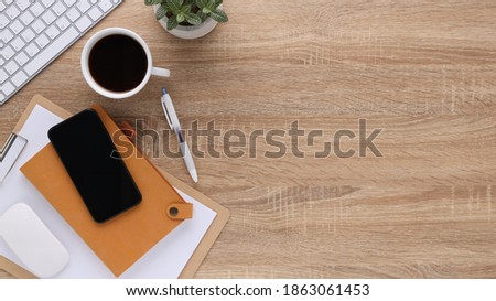 Top view wooden workspace office desk with computer and office supplies. Flat lay work table with blank notebook, keyboard, pen , smartphone and coffee cup. Copy space for your advertising content.
