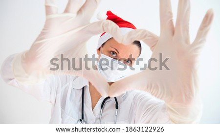 Woman doctor with a medical mask and hands in latex glove shows the symbol of the heart during the Christmas and New Year holidays. Royalty-Free Stock Photo #1863122926