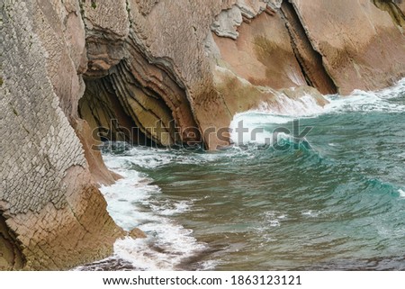 Photography of a cave in Basque country in summer day. It's time of low tide for Atlantic ocean in Bay of Biscay. Charming Zumaia Itzurun beach. High resolution photo.