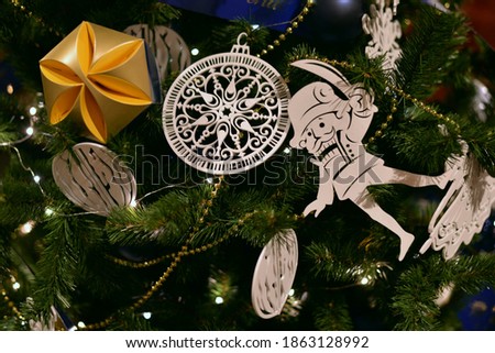 Openwork Christmas decorations made of white plywood balls, a clock and a nutcracker on the branches of a Christmas tree