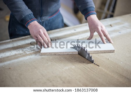 Closeup of wood cutting table with electric circular saw. Professional carpenter cutting wooden board at sawmill Royalty-Free Stock Photo #1863137008