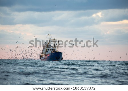 Return of the fishing seiner after the catch at sunset Royalty-Free Stock Photo #1863139072