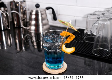 Mojito cocktail with fresh orange. Iced blue lagoon alcohol cocktail drink with orange, white marble background copy space