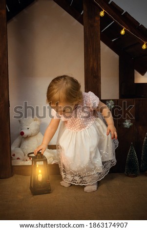 Christmas scenery in the studio, a little girl with a magic flashlight, a candle. Magical New Year, art photography, on Christmas night.