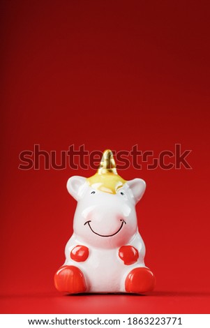 Unicorn figurine on a red background with free space.