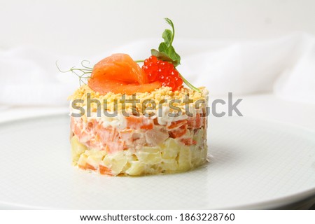 Traditional Russian Layer Salad Decorated Salmon Slice And Red Caviar On Grey Plate With Fork And Knife On White Table. Side View, Close Up.